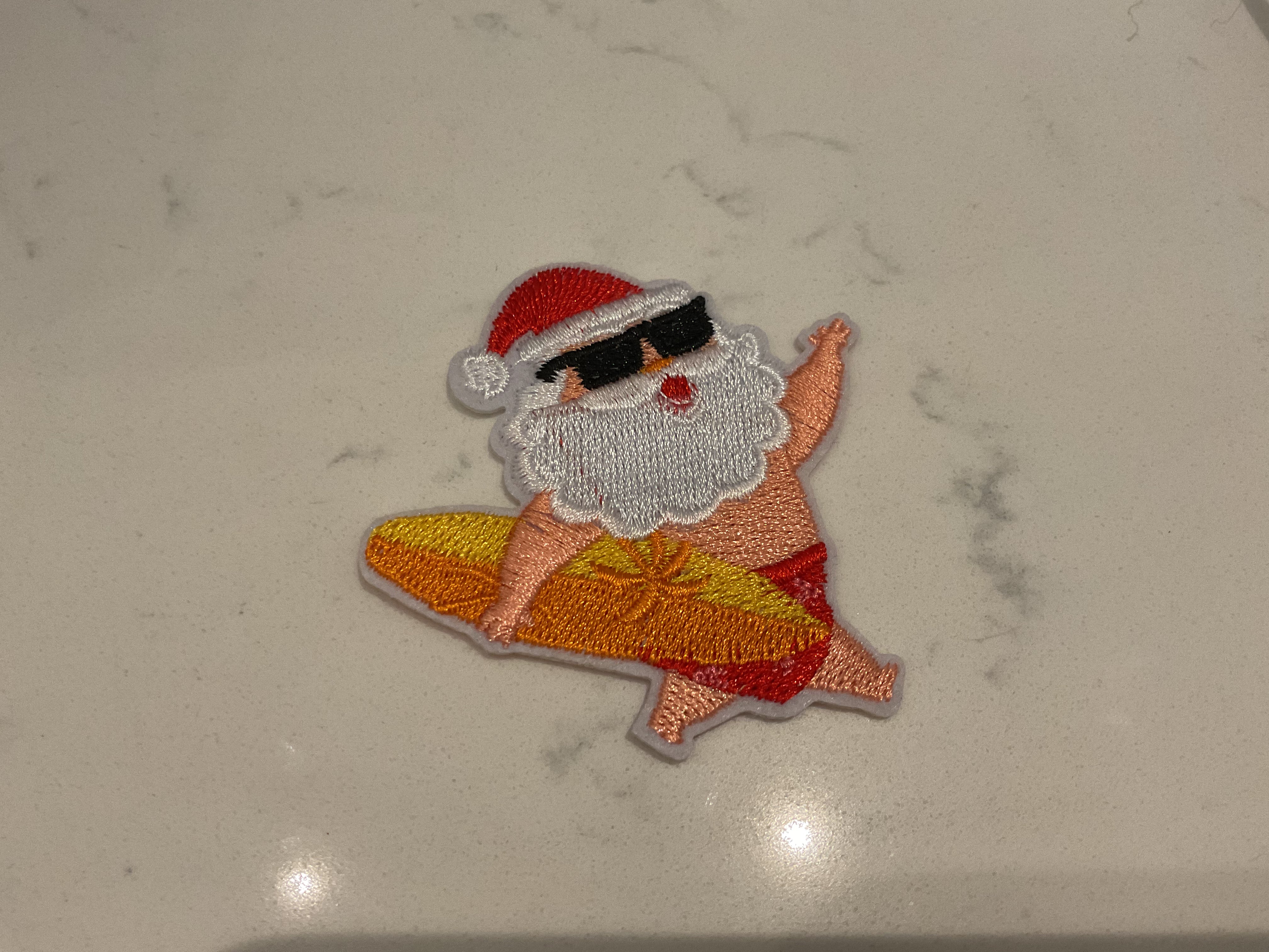 Santa holding an orange surfboard patch