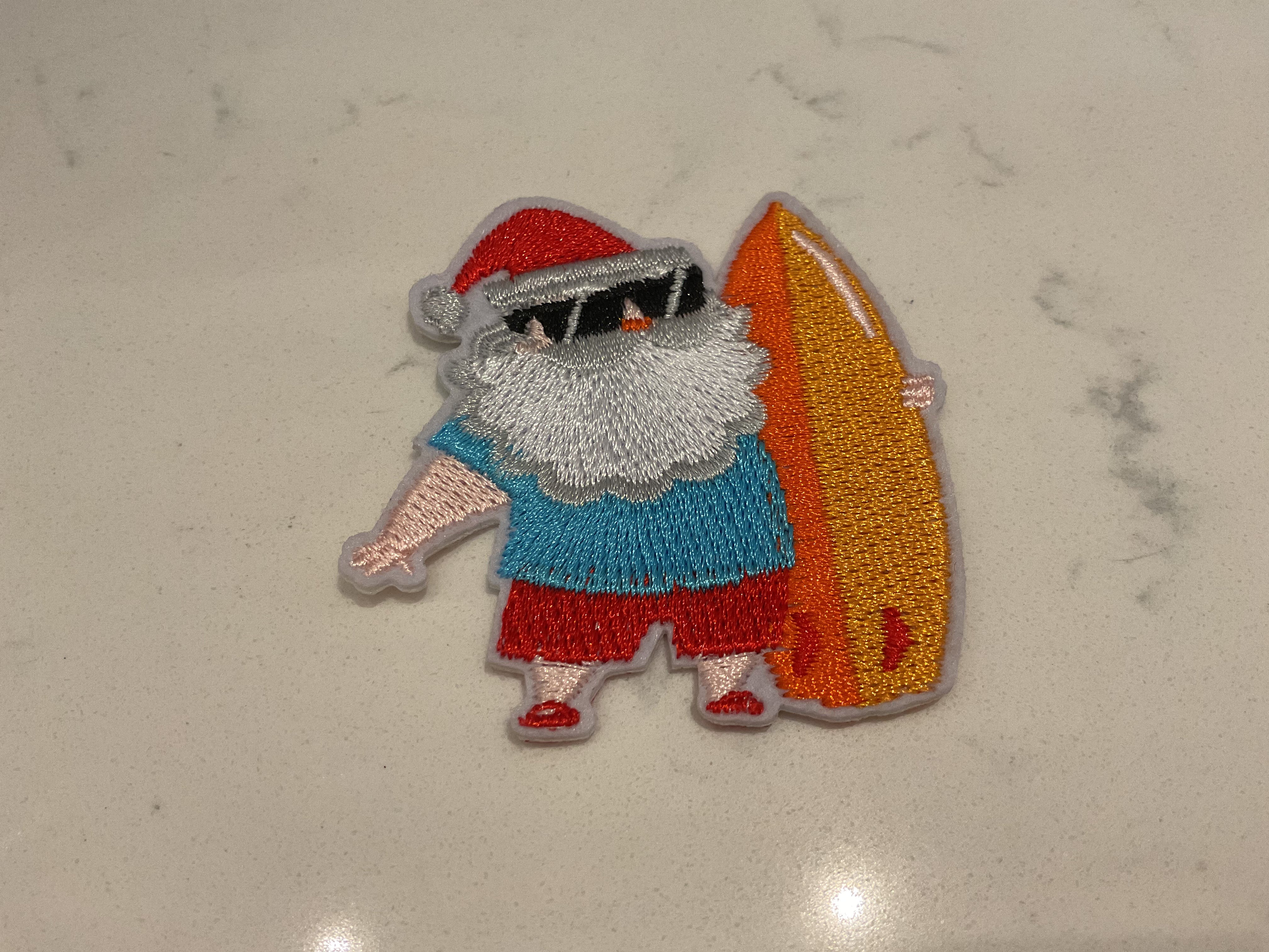 Santa holding an orange surfboard patch